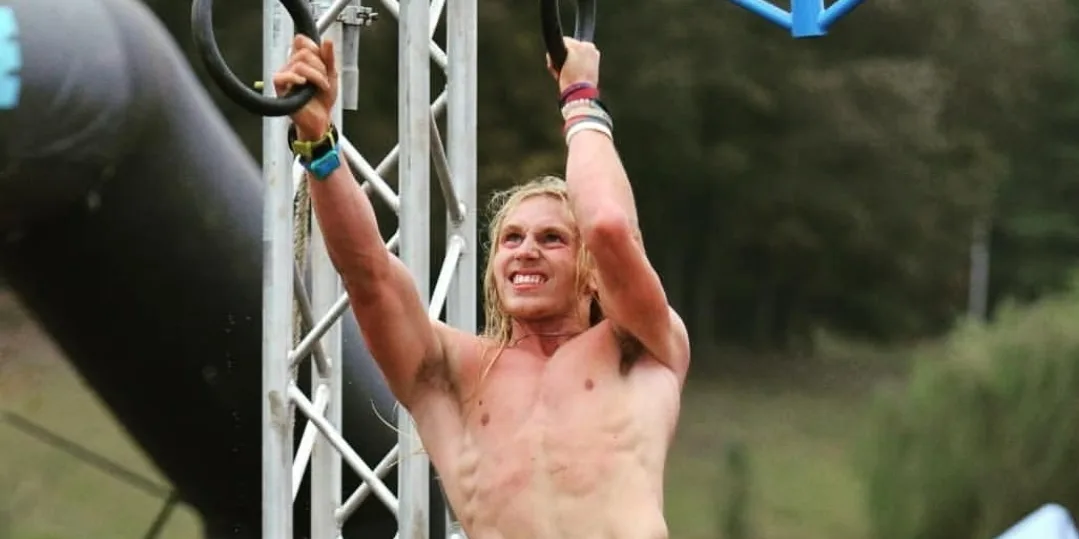 Cody Wood mid-swing on a rings obstacle during a Savage Race event